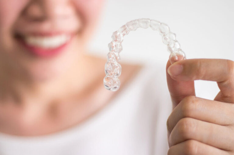 Girl Holding Invisalign With A White Shirt