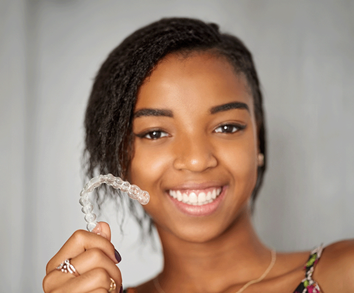Smiling Teen Girl Holding Clear Aligner
