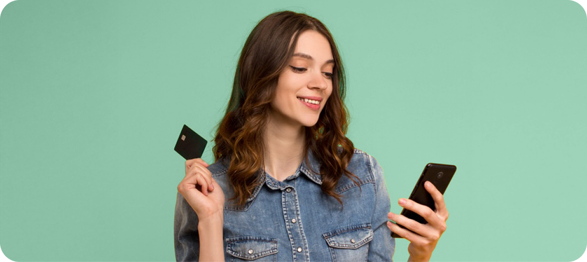 Woman Looking At Phone Holding Credit Card