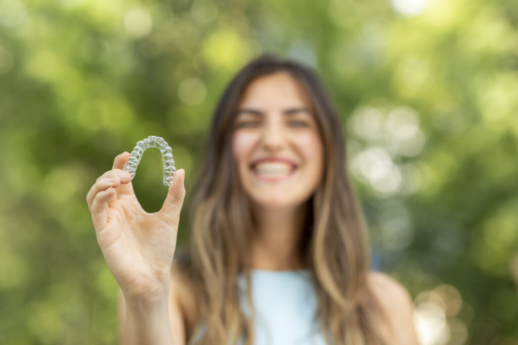 Beautiful smiling woman is holding an Invisalign bracer