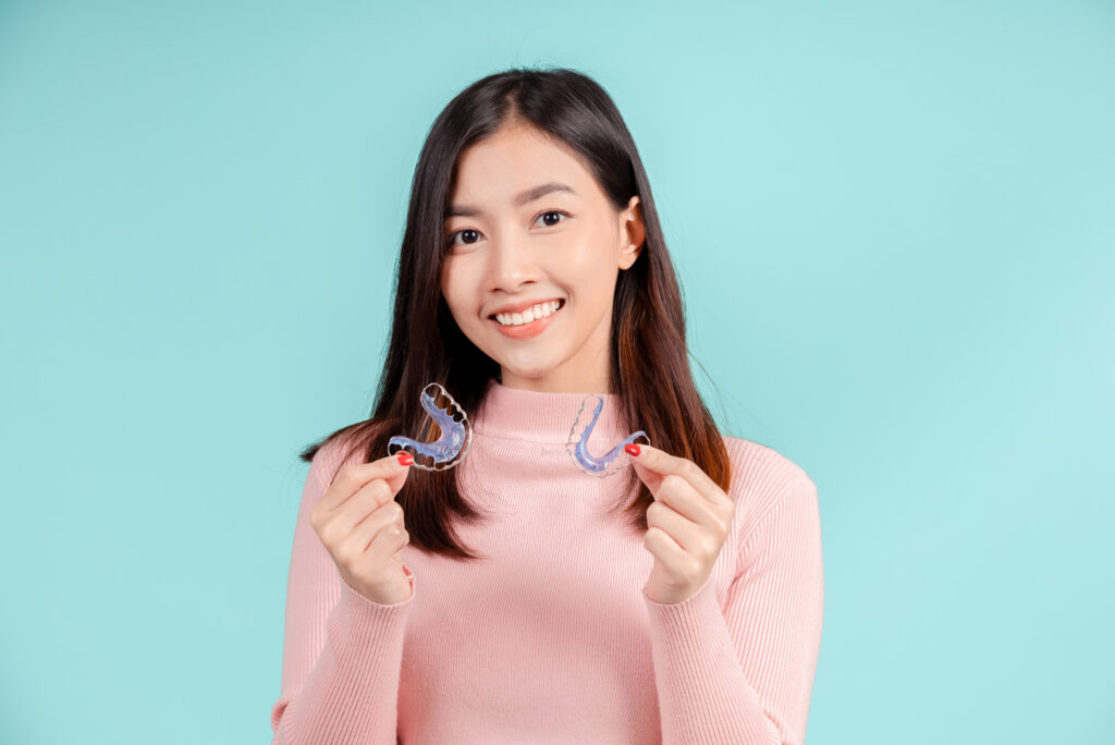 smiling of young woman holding retainers with white teeth and increased confidence