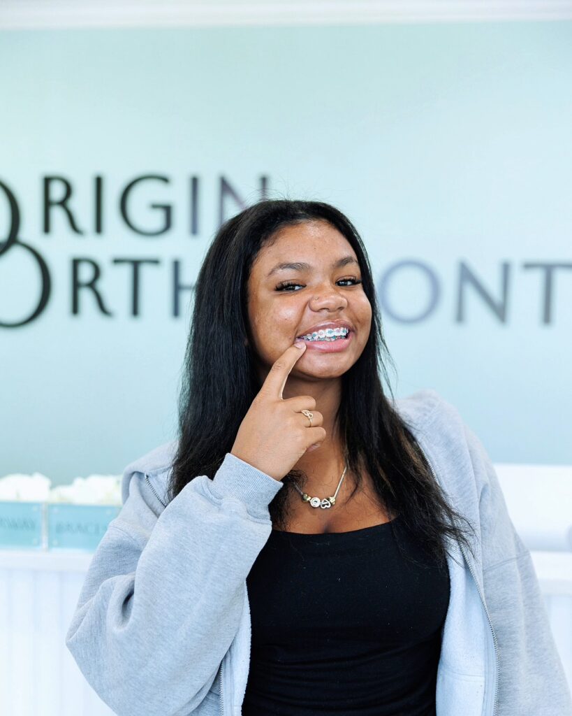 Smiling Patient With Braces Pointing At Her Teeth